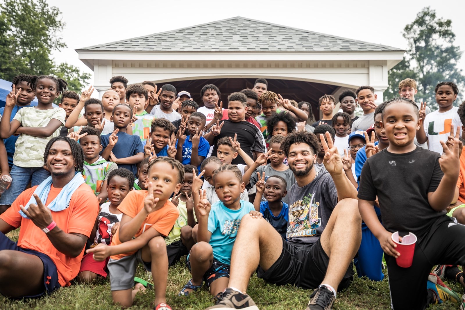 Caleb Williams with kids, holding a peace sign